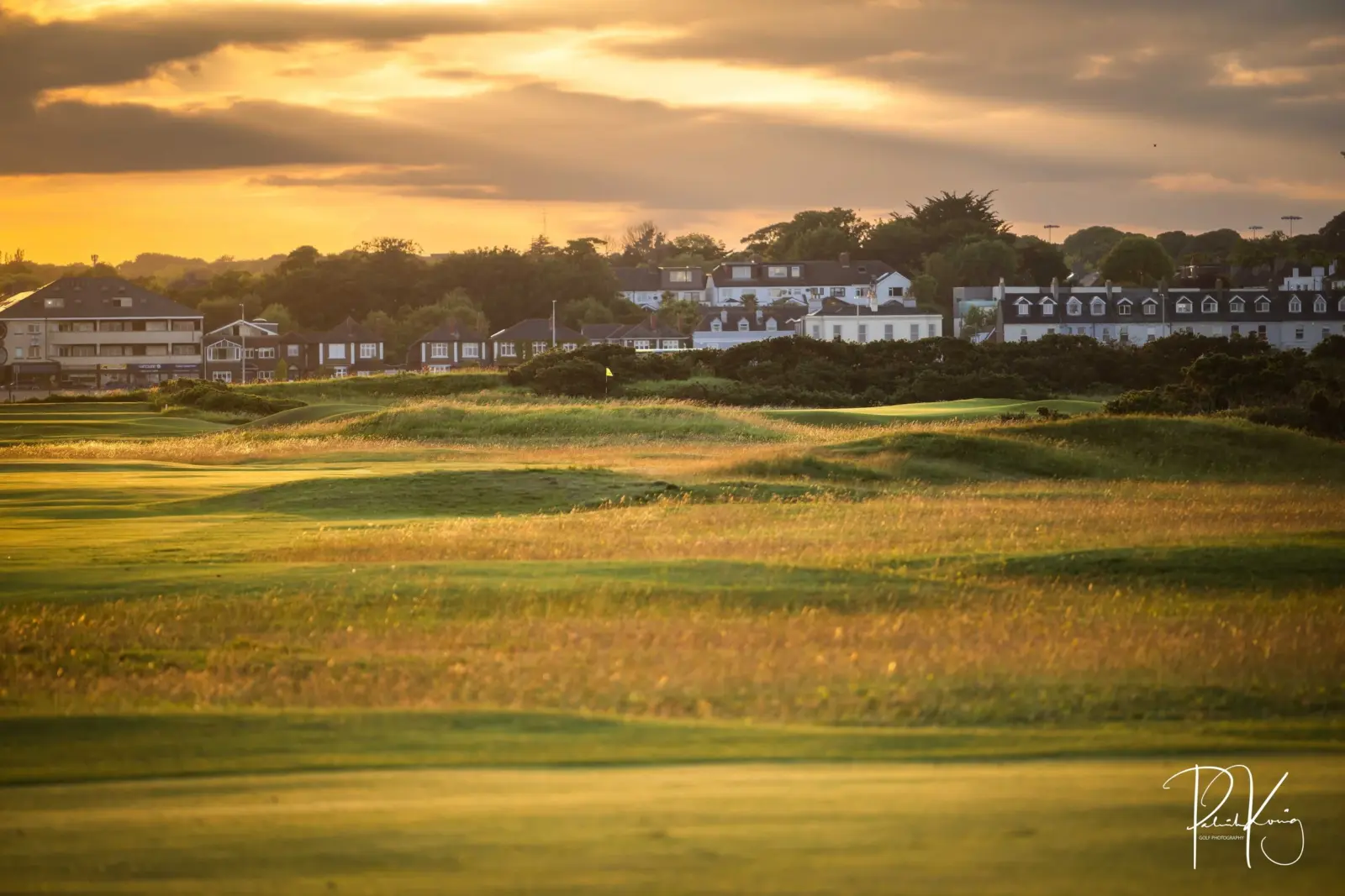 Aerial editorial photograph of a golf course fairway at sunrise showing the green and surrounding