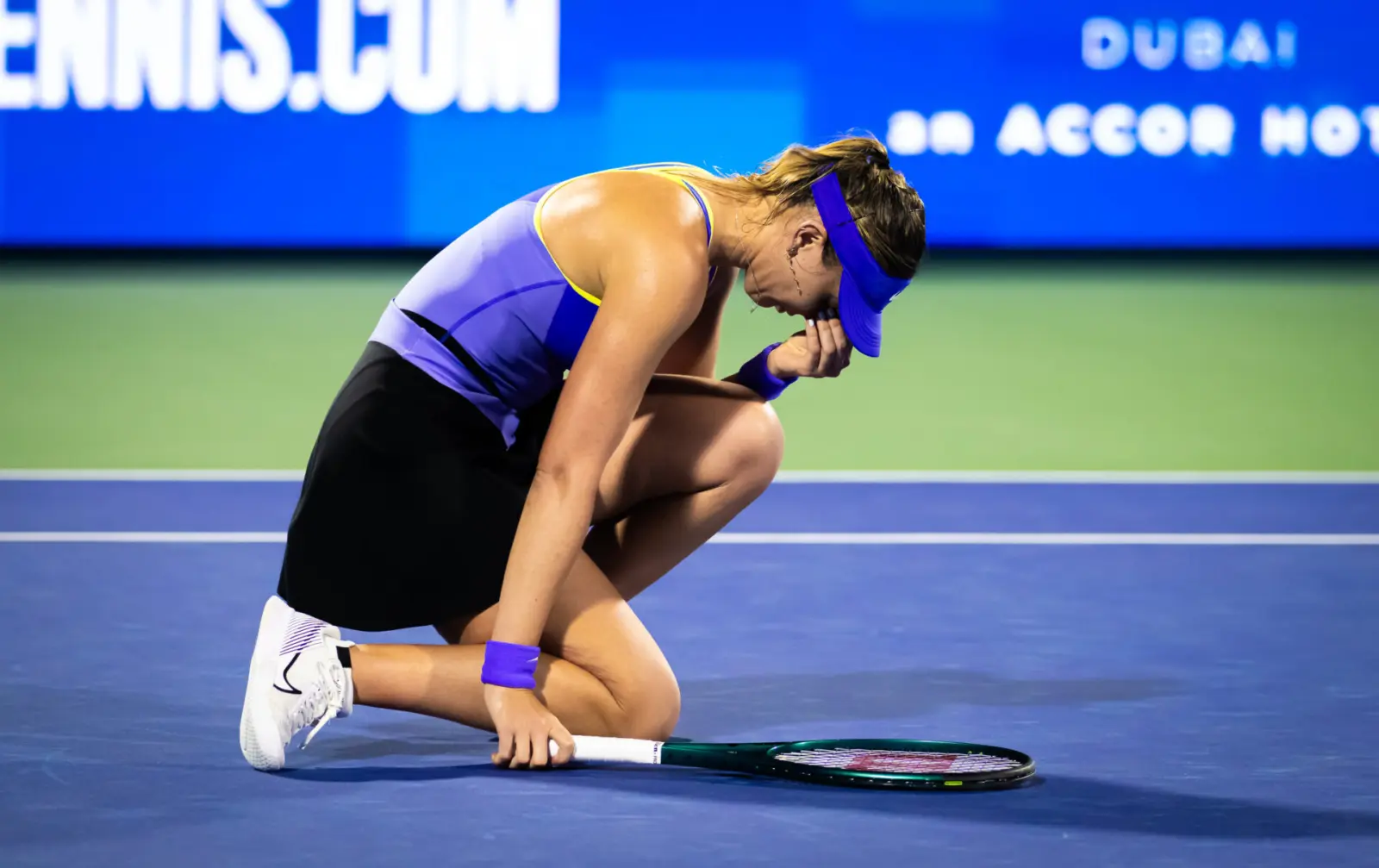 Tennis player serving during a Grand Slam match under natural stadium lighting in wide editorial
